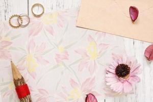 papel floral con anillos, lápiz y flor foto