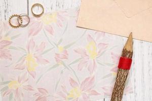 papel floral con anillos y un lápiz foto