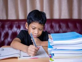 boy doing homework and reading on a wooden table . photo