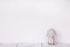 Ceramic doll on white wall photo