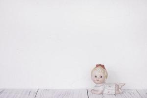 Ceramic doll on white wall photo