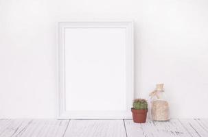 White frame with plant and bottle photo