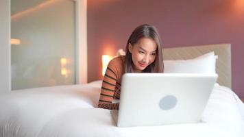 joven, mujer asiática, utiliza, un, computador portatil, en cama video