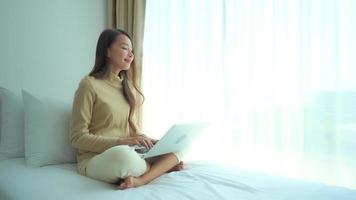 jovem asiática usando um laptop na cama