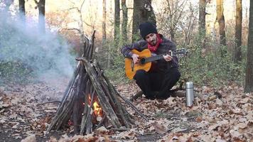 jonge mannelijke reiziger in het herfstbos speelt alleen op gitaar video