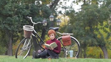 jonge vrouw met boek en fiets in park