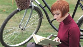 mujer joven, con, libro, y, bicicleta, en el estacionamiento video