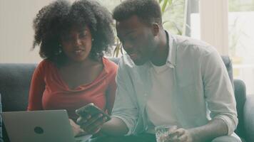 Woman and man sitting on couch talking whilst watching smartphone video