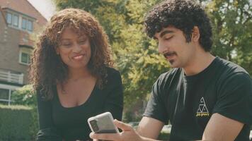 Man holds smartphone and talks about it with woman in park video