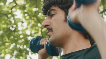 Homme debout dans le jardin soulevant des haltères video