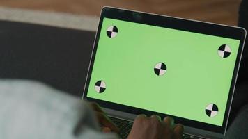 primo piano del laptop con schermo verde con le dita di digitazione dell'uomo