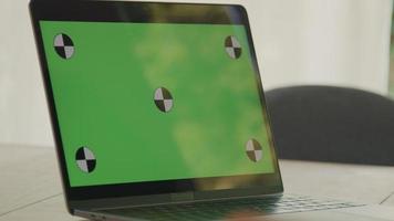 primo piano del computer portatile con schermo verde sul tavolo con la mano che gesticola video