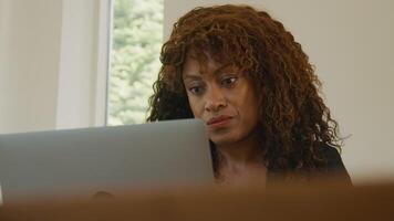 Woman sitting at table with laptop staring and thinking video