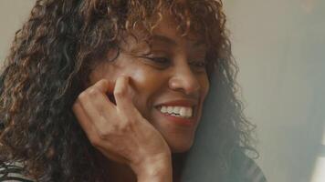 Close up of woman listening and smiling to person sitting next to her video