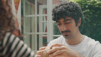 L'homme à table dans le jardin parle avec la femme tout en regardant le petit pain video