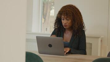 Woman sitting at table typing on laptop video