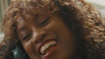mujer con auriculares acostada boca arriba cantando, sonriendo y moviéndose video