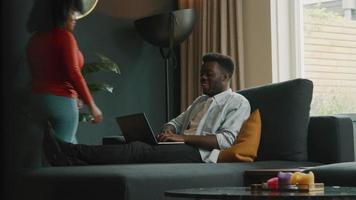 uomo seduto sul divano con laptop e donna si unisce?