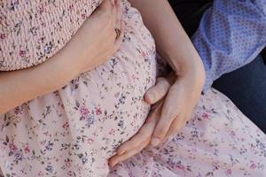 2 pares de manos abrazando el estómago de una mujer embarazada foto