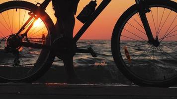 silhuett av ung man med cykel på morgonstranden under soluppgången