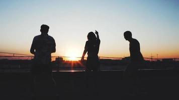 Silhouetten einer Gruppe von Menschen auf dem Dach bei Sonnenuntergang video