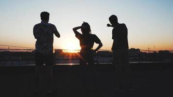 siluetas de un grupo de personas en la azotea durante la puesta de sol video