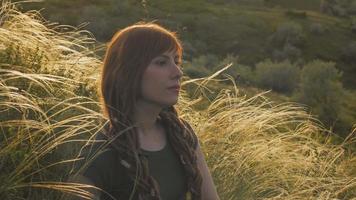 Mujer joven con rastas rojas relajándose en los campos video