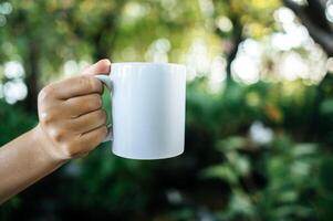 taza blanca en la mano en tiempo de relajación foto