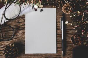 A blank card, glasses and a pen is placed on wood. photo