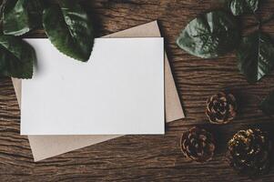 A blank card is placed on envelope and leaf with wood background photo