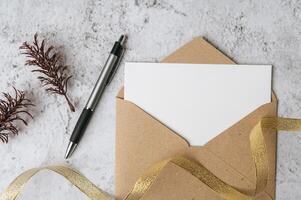 A blank card with envelope, pen and leaf is placed on white background photo