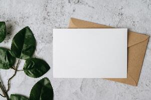 A blank card with envelope and leaf is placed on white background photo