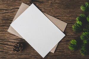 A blank card is placed on envelope and leaf with wood background photo