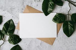 A blank card with envelope and leaf is placed on white background photo