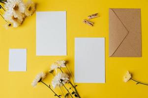 blank card with envelope and flower is placed on yellow background