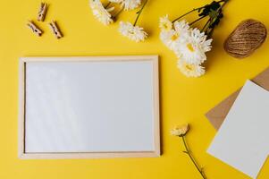 White board with envelope and flower is placed on yellow background photo