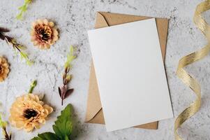 Se coloca una tarjeta en blanco con sobre y flor sobre fondo blanco. foto