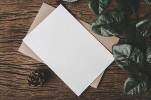 A blank card is placed on envelope and leaf with wood background photo