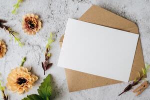 Se coloca una tarjeta en blanco con sobre y flor sobre fondo blanco. foto