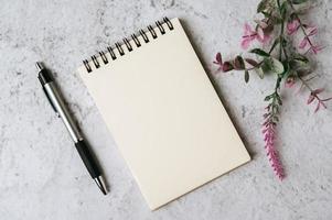 notebook, pen and flower is placed on white background photo