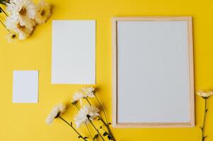 White board , blank card and flower is placed on yellow background photo