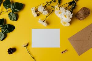 A blank card with envelope and flower is placed on yellow background photo