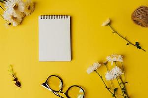 Cuaderno, vasos y flor se coloca sobre fondo amarillo. foto