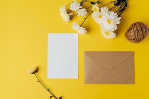 A blank card with envelope and flower is placed on yellow background photo