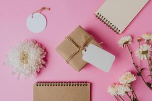 gift box, flower and a book on pink background photo