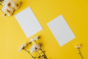 Dos tarjetas en blanco con flores se colocan sobre fondo amarillo. foto