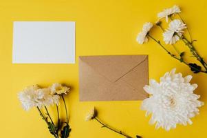 A blank card with envelope and flowers is placed on yellow background photo