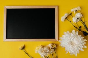 Black board and flower is placed on yellow background photo