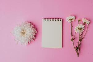 cuaderno con flor sobre fondo rosa foto