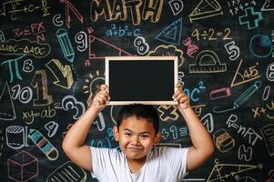 niño de pie y sosteniendo la pizarra en el aula foto